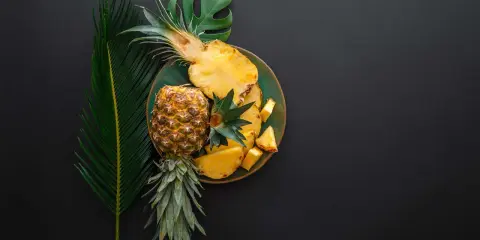 Ananas na talerzu, obok liści. Czy wiesz, że bromelaina co to za enzym?