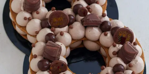 Gâteau number cake chocolat, décoré de crème onctueuse, de chocolats et de billes croquantes. Parfait pour une recette number cake chocolat d'anniversaire.