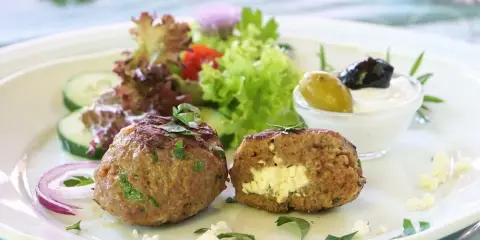 Gefüllte Bifteki mit Feta, serviert mit Salat, Gurken, Zwiebeln und Tzatziki. Ein köstliches Bifteki Rezept für Genießer.