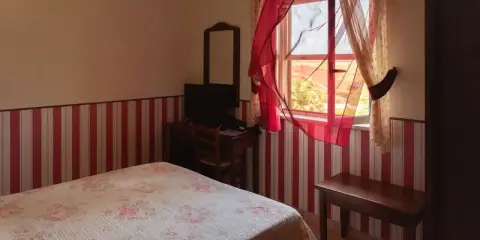 Camera accogliente in un agriturismo a Lamezia Terme, con letto fiorato e tende rosse che danzano al vento.
