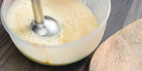 Préparation d'une recette mayonnaise maison avec un mixeur plongeant dans un bol. La texture commence à s'épaissir.