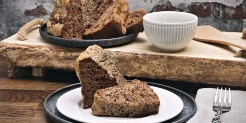 Saftiger **Diabetiker Kuchen** auf rustikalem Holzbrett, serviert auf Tellern mit Gabel.