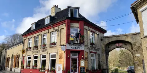 Façade de la Taverne Vauban à Bergues, avec une enseigne et une décoration de cycliste.