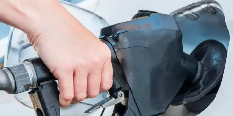 Dłoń trzyma pistolet paliwowy, rozpoczynając tankowanie samochodu.