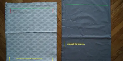 Dwa kawałki materiału na podłodze, jeden z rybkami, drugi szary. Pokazują etapy, jak uszyć plecak, zaznaczone linie i miejsca do zszycia.