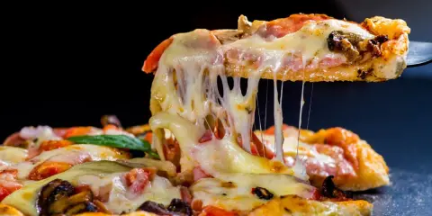 Rozciągający się ser z kawałka pysznej pizzy z kurczakiem, pomidorami i grzybami.