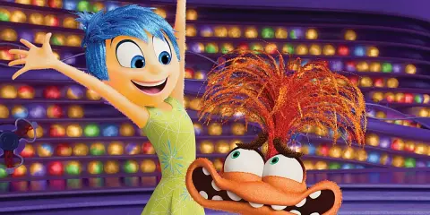 Alegría, del reves 2, salta feliz junto a un personaje naranja con pelo de fuego y ojos saltones, en un escenario de luces de colores.