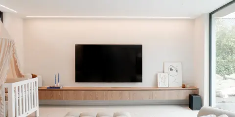 Meuble TV en bois clair, suspendu, offrant une belle profondeur. Une télévision est fixée au mur au-dessus.