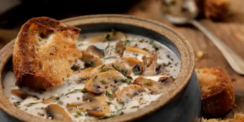 Una cremosa zuppa di funghi toscana, arricchita da erbe aromatiche e servita con crostini di pane abbrustolito.