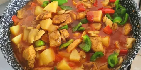Gulasz z kurczaka w sosie pomidorowym z ziemniakami, papryką i pieczarkami, gotowy do podania.