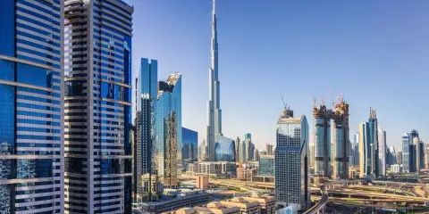 Nowoczesne wieżowce Dubaju, w tym Burj Khalifa, na tle błękitnego nieba. Widać autostrady i linie lotnicze Dubaj.
