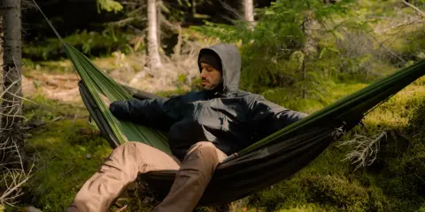 Mężczyzna w hamaku w lesie. To jest właśnie bushcraft – sztuka przetrwania i życia w zgodzie z naturą.