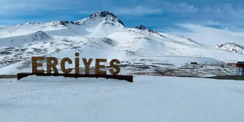 Zimowy krajobraz z napisem "ERCIYES" na tle ośnieżonych gór. Idealne miejsce na narty w Erciyes Ski Resort.