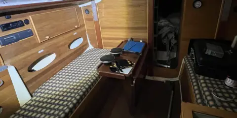 Intérieur d'un voilier Trident 80. Banquette, table pliante, rangement et couchette.