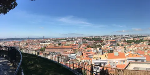 Blick vom Nossa Senhora do Monte auf Lissabon mit seinen roten Dächern und der Brücke im Hintergrund.