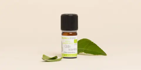 Flacon d'huile essentielle de ciste, aux vertus uniques et régénérantes, accompagné de feuilles vertes.