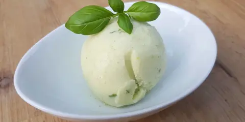 Une boule de sorbet citron vert et basilic, parfaite pour une recette sorbet citron professionnel. Délicatement garnie de feuilles de basilic frais.