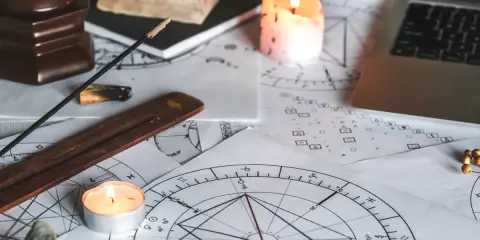 Świece i kadzidełka tworzą mistyczną atmosferę wokół kart astrologicznych. 11 dom astrologia w centrum uwagi.
