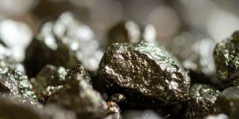 Zbliżenie na błyszczące bryłki pirytu, ukazujące jego metaliczny połysk i nierówną powierzchnię. Piryt właściwości tego minerału fascynują.