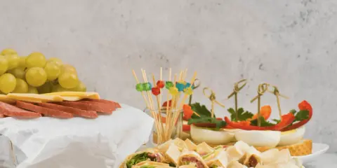 Kolorowe, zdrowe przekąski na imprezę: koreczki z warzywami, jajka faszerowane, roladki z tortilli, winogrona, ser i salami.