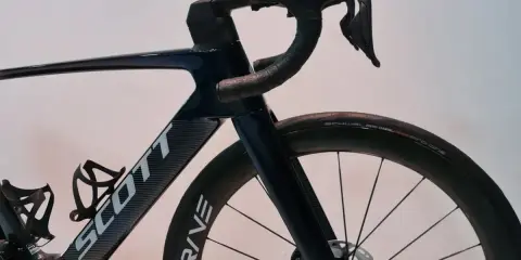 Ciemnoniebieski rower Scott z aerodynamicznym mostkiem i kierownicą. Koła z oponami Schwalbe Pro One.