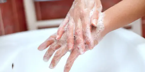 Mani insaponate che dimostrano come è fatto il sapone, creando una schiuma soffice per pulire.