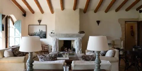 Acogedor salón comedor de casa de campo con vigas de madera, chimenea de piedra y sofás confortables.