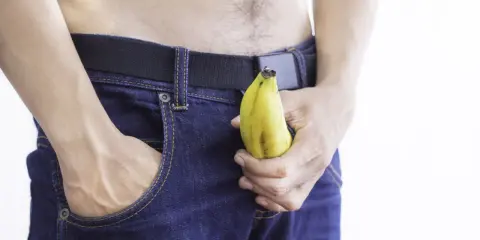 Mężczyzna w dżinsach trzyma banana, sugerując jelqing efekty.