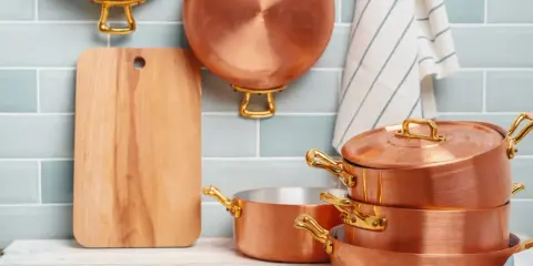 Utensilios de cobre apilados y colgados, listos para aprender como limpiar el cobre y mantenerlos brillantes.