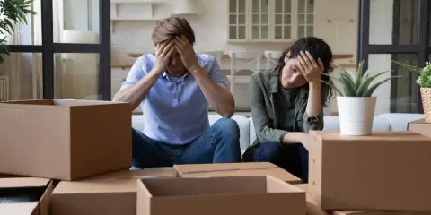 Couple overwhelmed by the stress of moving, surrounded by moving boxes.