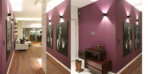 Nowoczesny przedpokój w bloku inspiracje: fioletowe ściany, drewniana podłoga, grafiki i stylowe oświetlenie tworzą elegancką przestrzeń.