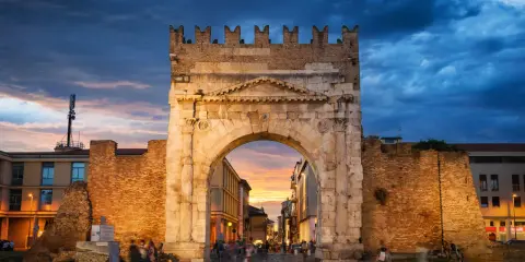 Arco d'Augusto a Rimini al tramonto, con il suo skyline suggestivo e le nuvole drammatiche.