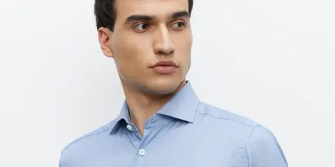 Mężczyzna w błękitnej koszuli z subtelnym wzorem i eleganckim kołnierzykiem włoskim.