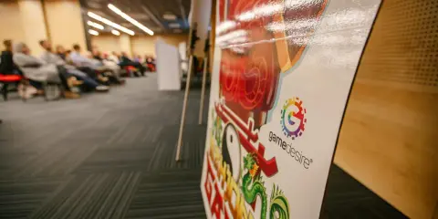 Na konferencji o grach planszowych, z bliska widać planszę z logo "gamedesire" i smoczym motywem.