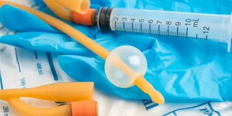 Cewnik, strzykawka i rękawiczki. Przygotowanie do założenia cewnika u pacjenta w domu.