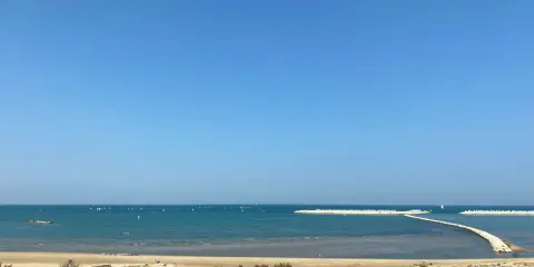 Piękny dzień nad morzem w Pescara i okolice. Wiele żaglówek na turkusowej wodzie, piaszczysta plaża i falochrony.