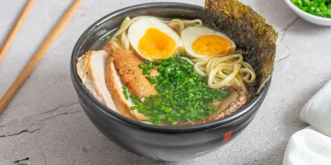 Un delicioso tazón de ramen con fideos, huevo cocido, carne de cerdo, cebollín y alga nori. Una tentadora receta ramen lista para disfrutar.