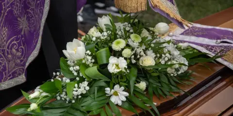 Białe lilie i inne kwiaty na trumnie, symbol pożegnania. Uroczysty bukiet na pogrzeb.