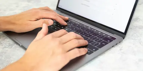 Dłonie piszą na laptopie. Może to być praca dla agencji copywriterskich, tworzenie treści lub analiza danych.