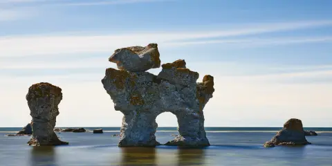 Raukar i havet vid Fårö, Gotland. En fantastisk vy att se på Gotland, med stenformationer som reser sig ur det blå vattnet under en molnig himmel.