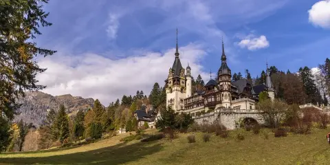 Zamek Peles w Rumunii na tle gór i jesiennego krajobrazu.
