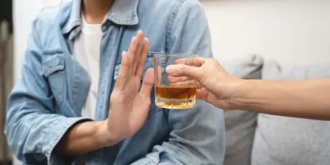 Mężczyzna odmawia alkoholu, symbolizując dobrowolne leczenie odwykowe i nowy początek.