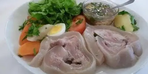 Une assiette de tête de veau gastronomique, accompagnée de légumes frais, d'un œuf dur, de carottes et d'une sauce savoureuse.