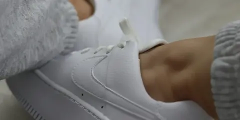 Białe sneakersy z szarym swetrem. Dowiedz się, jak zabezpieczyć białe buty, by długo wyglądały jak nowe.