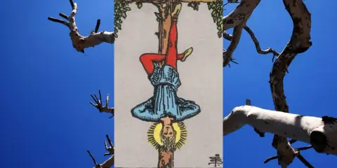 Karta tarota Wisielec (XII) na tle błękitnego nieba i gałęzi drzewa.