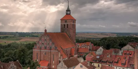 Gotycka ceglana architektura i malowniczy krajobraz Mazur, świadectwo bogatej historii regionu.