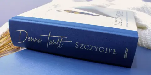 Granatowa okładka książki "Szczygieł" Donny Tartt z wytłoczonym złotym napisem.