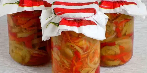 Słoiki z pyszną sałatką z pomidorów na zimę, ozdobione serwetkami z chili.