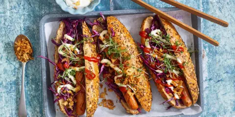 Drei leckere Hotdogs mit Rotkohl, Kresse und Röstzwiebeln – perfekt für vegetarisches Grillen!