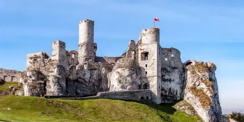 Ruiny zamku na skale, część Szlaku Orlich Gniazd, z polską flagą na wieży.